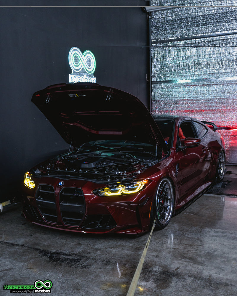 Red BMW G82 M4 with hood open on the dyno at Racebox