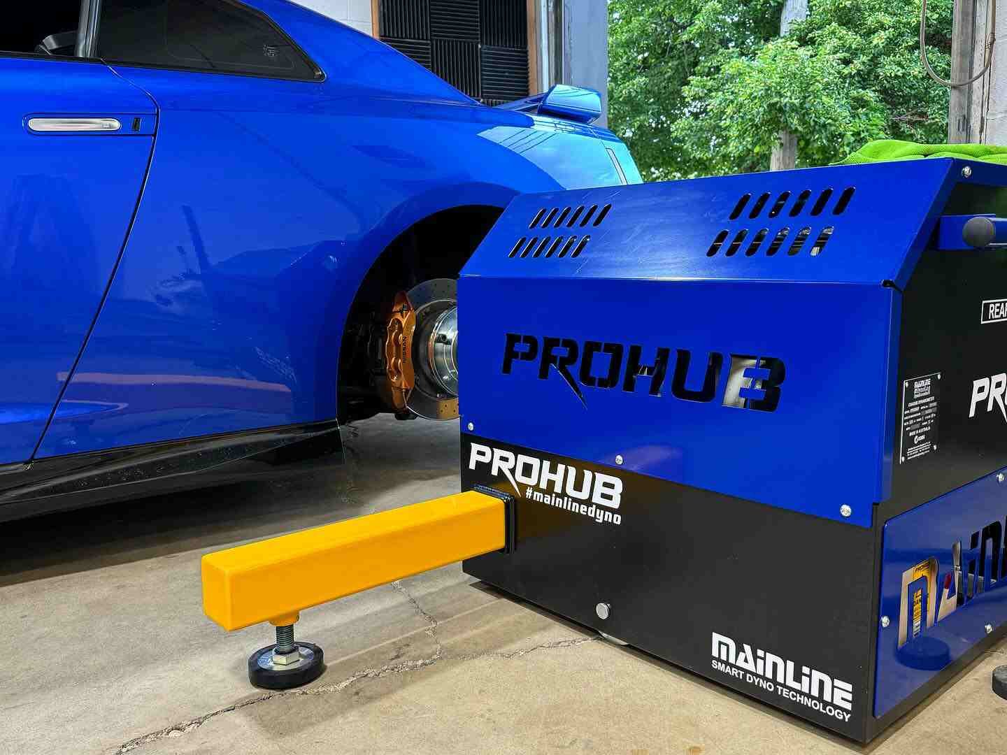 Mainline ProHub dyno mounted to a blue R35 GTR's hubs in a tuning shop